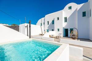 a swimming pool in front of a white building at Santa Irina Luxury Sunny Lofts in Perivolos