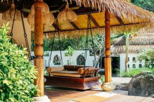 a porch swing with a couch under a straw umbrella at Zazen Boutique Resort & Spa in Bophut