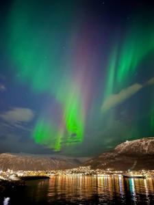 un'aurora nel cielo sopra un corpo d'acqua di Leilighet ved havet med utsikt over Tromsøysundet. a Tromsø