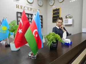 una mujer hablando en un celular en una habitación con banderas en Cityland Hotel Baku, en Baku