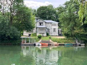 Charmant appartement 1930 Centre-ville Nogent-sur-Marne في نوجينت-سور-مارن: منزل على شاطئ بحيرة مع قارب