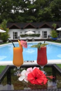 three cocktails sitting on a table near a pool at Sunz en Coron Resort in Coron
