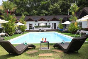 a swimming pool with two chairs and a house at Sunz en Coron Resort in Coron