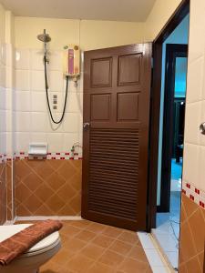 ein Bad mit einer braunen Tür und einem WC in der Unterkunft Hideaway House Patong in Patong Beach
