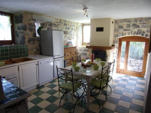 Una cocina con una mesa y sillas en una habitación. en Gîte L'ESCOUSSOU 6p, 4ch, 120m2, charme et nature, piscine chauffée, sud Ardèche, en Joyeuse
