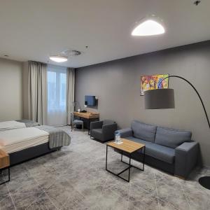 um quarto de hotel com uma cama e um sofá em Hotel Centrum em Bolesławiec