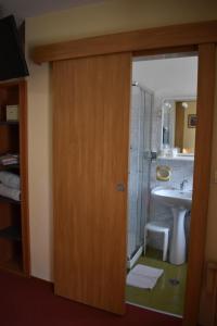 a bathroom with a shower and a sink and a door at Albergo Pensione Sport in Arabba