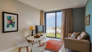 a living room with a couch and a tv and a table at The View, Apartment, with magnificent sea view in Hermanus