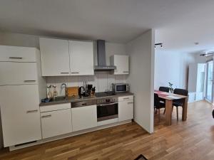uma cozinha com armários brancos, uma mesa e uma sala de jantar em Stylish Apartment in Innsbruck + 1 parking spot em Innsbruck