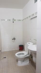 La salle de bains blanche est pourvue de toilettes et d'un lavabo. dans l'établissement Khách sạn Hoàng Long, à Hô-Chi-Minh-Ville