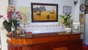 un escritorio con flores y una foto en la pared en Khách sạn Hoàng Long, en Ho Chi Minh