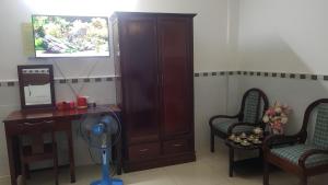 a room with a fan and two chairs and a tv at Khách sạn Hoàng Long in Ho Chi Minh City