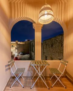 a table and chairs on a balcony with a chandelier at House 76 in Nizwa