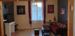 a living room with a red couch and a window at Bourgueil - Grand appartement proche CNPE Chinon in Bourgueil