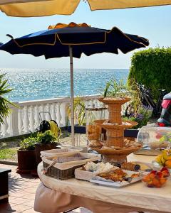 einen Tisch mit einem Regenschirm und etwas Essen drauf in der Unterkunft Hotel Golfo e Palme in Diano Marina