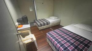 Cette petite chambre comprend deux lits et une télévision. dans l'établissement HOTEL 59, à Sibu