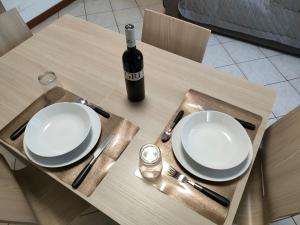 einen Tisch mit zwei weißen Tellern und einer Flasche Wein in der Unterkunft Ca' Ida - Affitti Temporanei in Turin