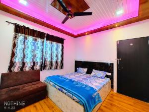 a bedroom with a bed and a couch and pink lights at Hotel Unnat Shree. in Pachmarhī