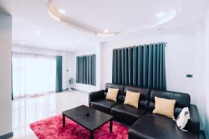 a living room with a black leather couch and a red rug at AABAN House 01 in Hat Yai