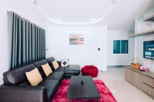 a living room with a black leather couch and a table at AABAN House 01 in Hat Yai