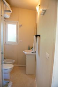 a bathroom with a sink and a toilet and a window at Campeggio Bocca di Cecina in Marina di Cecina