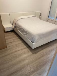 Cosy Colour Place في فيليرز سور مارن: سرير أبيض في غرفة ذات أرضية خشبية