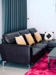 a black leather couch with pillows on a red rug at AABAN House 01 in Hat Yai