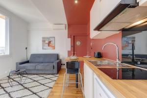 una cocina con fregadero y un sofá en una habitación en Terracotta-T2-Clim-Parking gratuit privé, en Pierre-Bénite