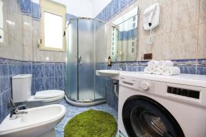 a washing machine in a bathroom with a toilet and a sink at Noa Apartments in Vlorë +81 photos