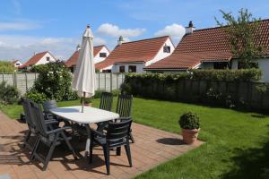 einen Tisch und Stühle mit Sonnenschirm im Hof in der Unterkunft Vakantiehuisje De Haan in De Haan