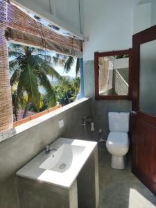 een badkamer met een wastafel, een toilet en een raam bij Arazo villa in Unawatuna