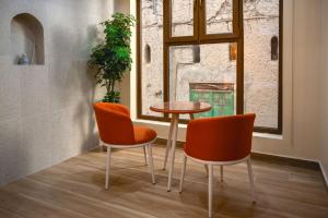 duas cadeiras cor-de-laranja e uma mesa num quarto em House 76 em Nizwa