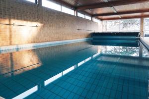 una gran piscina con azulejos azules en el suelo en Apartment mit Schwimmbad und Privatparkplatz, en Augsburg