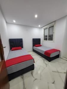 two beds in a room with white walls at Duplex+2 salles de bain à 5 min de l'aéroport in Marrakech