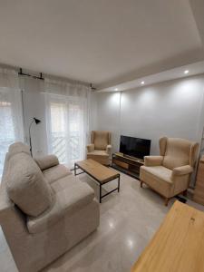 uma sala de estar com um sofá e duas cadeiras e uma televisão em Granada Centro Congresos em Granada