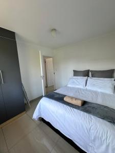 a bedroom with a large white bed with a wooden floor at Wood Road Apartments in Durban