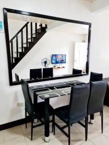 une table à manger avec des chaises noires et un grand miroir dans l'établissement Calapan Transient Molave L47, à Calapan
