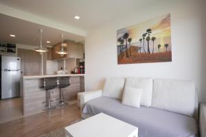 a living room with a couch and a kitchen at Calypso Condo Rawai Nai Harn beach in Rawai Beach