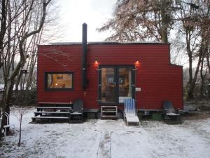 een rood tiny house met stoelen in de sneeuw bij Tinyhouse on wheels in Schortens