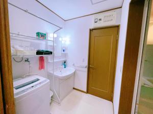een badkamer met een wastafel, een toilet en een deur bij Miyama House in Hachioji