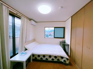 een kleine slaapkamer met een bed en een raam bij Miyama House in Hachioji