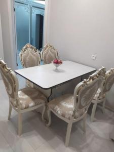 ein weißer Tisch und Stühle mit einer Obstschale darauf in der Unterkunft 1комнатная квартира in Bischkek
