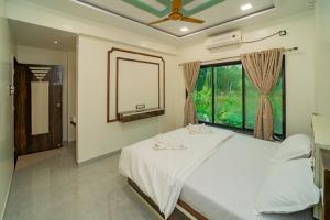 a bedroom with a white bed and a window at Happy Stay Villa - Kashid beach in Kashid