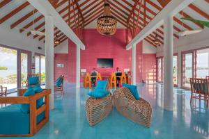 Habitación con mesa, sillas y pared roja. en OBLU NATURE Helengeli-All-Inclusive with free Transfers, en Atolón de Malé Norte