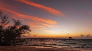 einen Sonnenuntergang am Strand mit einem Pier im Wasser in der Unterkunft OBLU NATURE Helengeli-All-Inclusive with free Transfers in Nord-Malé-Atoll