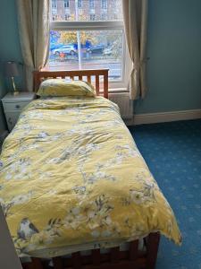 a bed with a yellow comforter and a window at Grace Stays in Ellesmere Port
