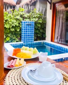 uma mesa com dois pratos de fruta e um bule de chá em Chalés Milagres Beach em São Miguel dos Milagres