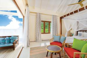 a bedroom with a bed and a table and chairs at OBLU NATURE Helengeli-All-Inclusive with free Transfers in North Male Atoll +140 photos