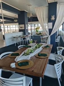 a dining room with a wooden table and white chairs at Hoedjiesbaai Hotel in Saldanha