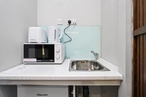 a kitchen counter with a sink and a microwave at Single Studio Flat in London